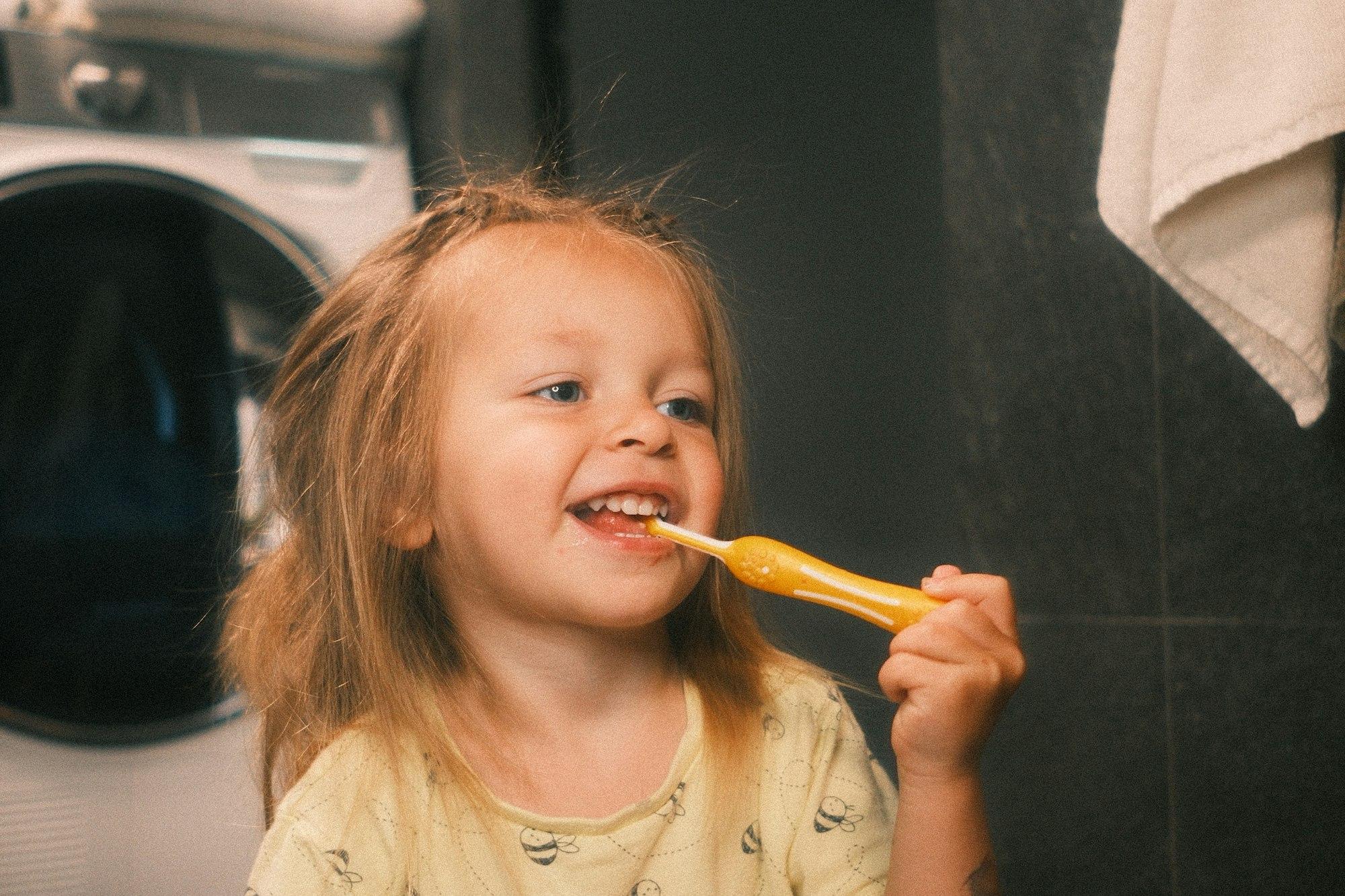 Smiling toddler brushing her teeth